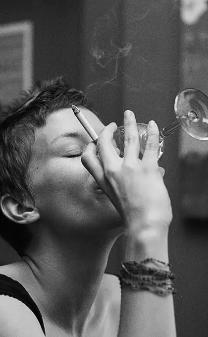 woman drinking wine while holding a cigarette